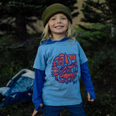 Smiling kid in a green beanie wearing the periwinkle Montana Nature Circle youth tee with a moose and canoe graphic
